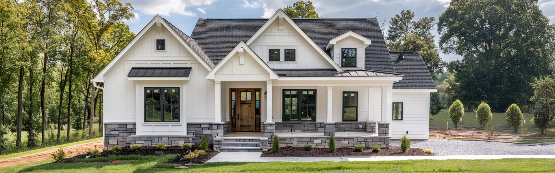Modern farmhouse front elevation with black-framed windows, white siding, and stone water table in the Raleigh Triangle.